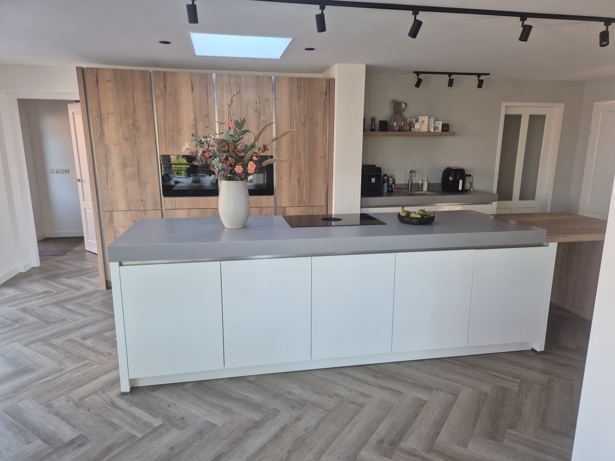 Wit keukeneiland met houten achterwand