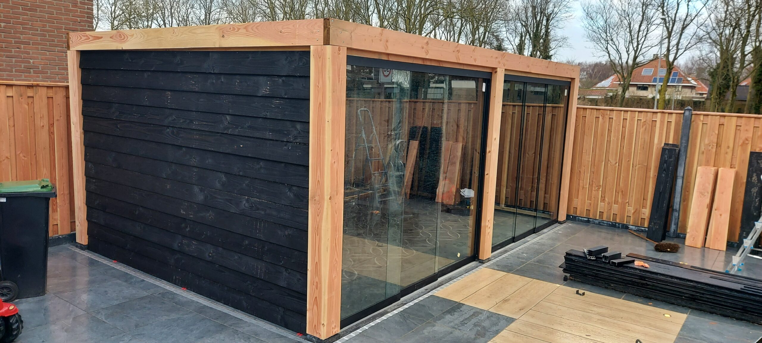 Zwart tuinhuis met glazen schuifpui in aanbouw
